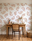 Verdant Scatter Terracotta tossed leaf wallpaper behind a vintage writing desk in a cozy craft-room home office