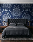 Vintage Eden Midnight damask wallpaper behind a tufted headboard in a dark, moody bedroom