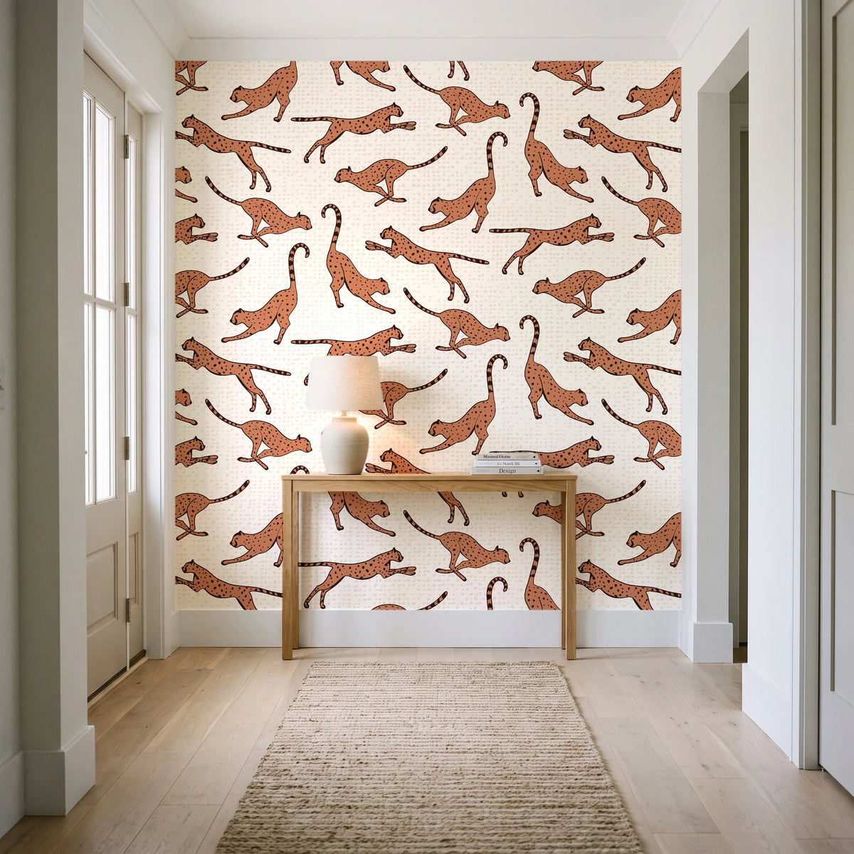 Wild Stride Terracotta cheetah wallpaper behind a console table in a light entry hallway