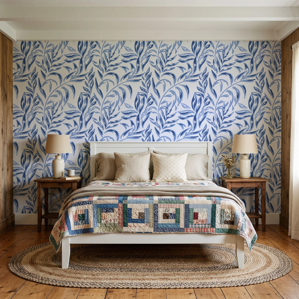 Willow Trace Indigo willow vine wallpaper behind a white cottage bed with a patchwork quilt in a cozy cottagecore bedroom
