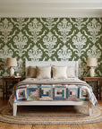 Woodland Blossom Veil Olive damask wallpaper behind a white cottage bed with a patchwork quilt in a cozy cottagecore bedroom