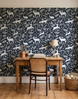 Woodland Hush Charcoal woodland animal wallpaper behind a vintage writing desk in a cozy craft-room home office