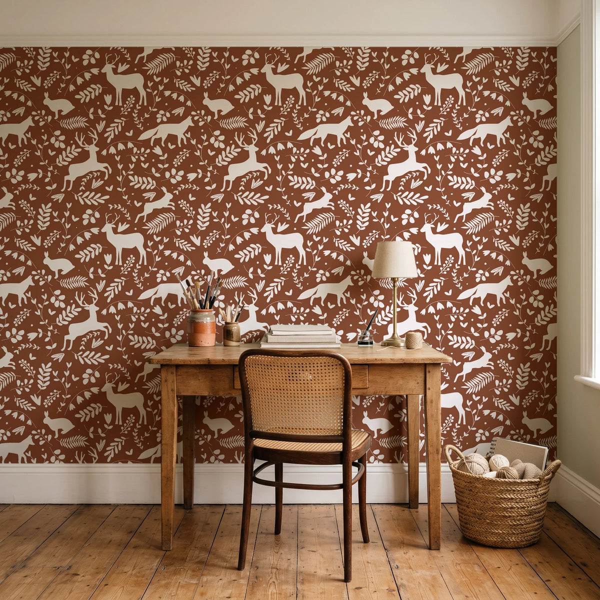 Woodland Hush Rust woodland animal wallpaper behind a vintage writing desk in a cozy craft-room home office
