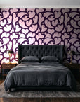 Woven Whisper Aubergine abstract heart wallpaper behind a tufted headboard in a dark, moody bedroom