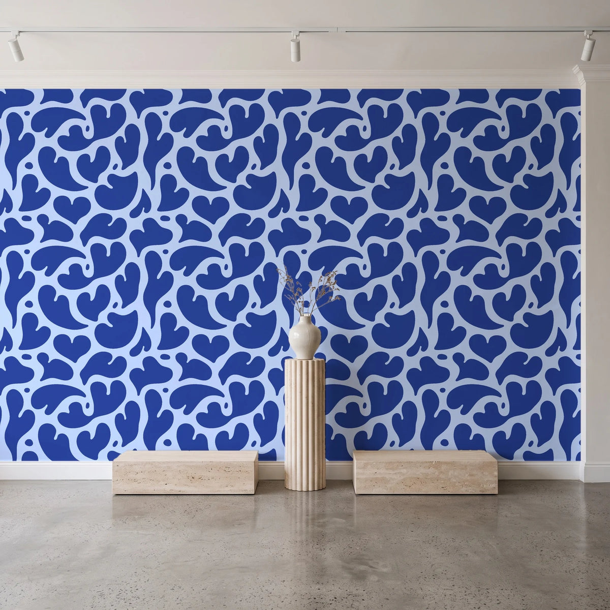 Woven Whisper Cobalt abstract heart wallpaper behind a travertine pedestal and vase in a minimal boutique