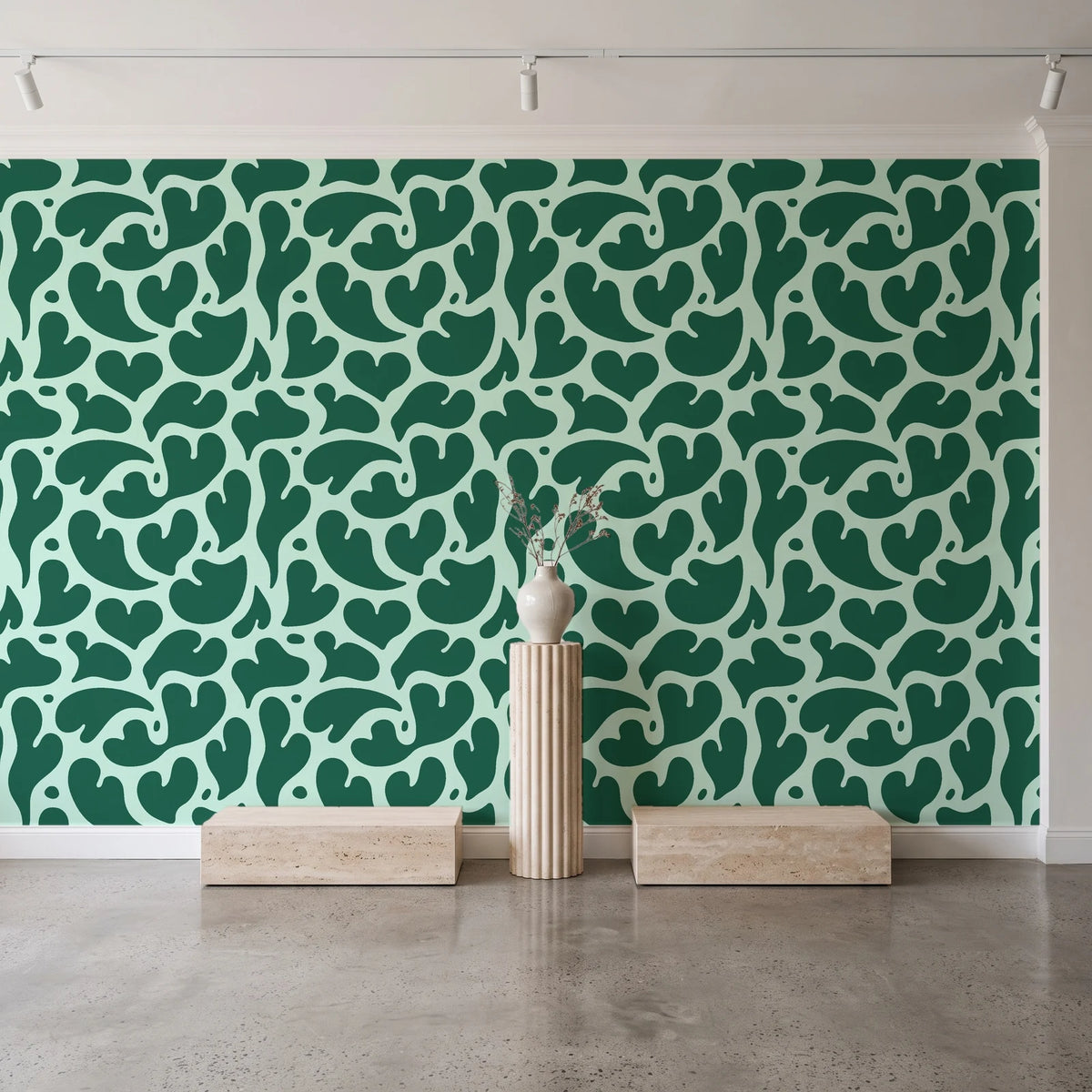 Woven Whisper Emerald abstract heart wallpaper behind a travertine pedestal and vase in a minimal boutique