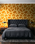 Woven Whisper Marigold abstract heart wallpaper behind a tufted headboard in a dark, moody bedroom