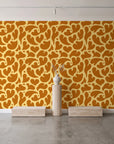 Woven Whisper Marigold abstract heart wallpaper behind a travertine pedestal and vase in a minimal boutique